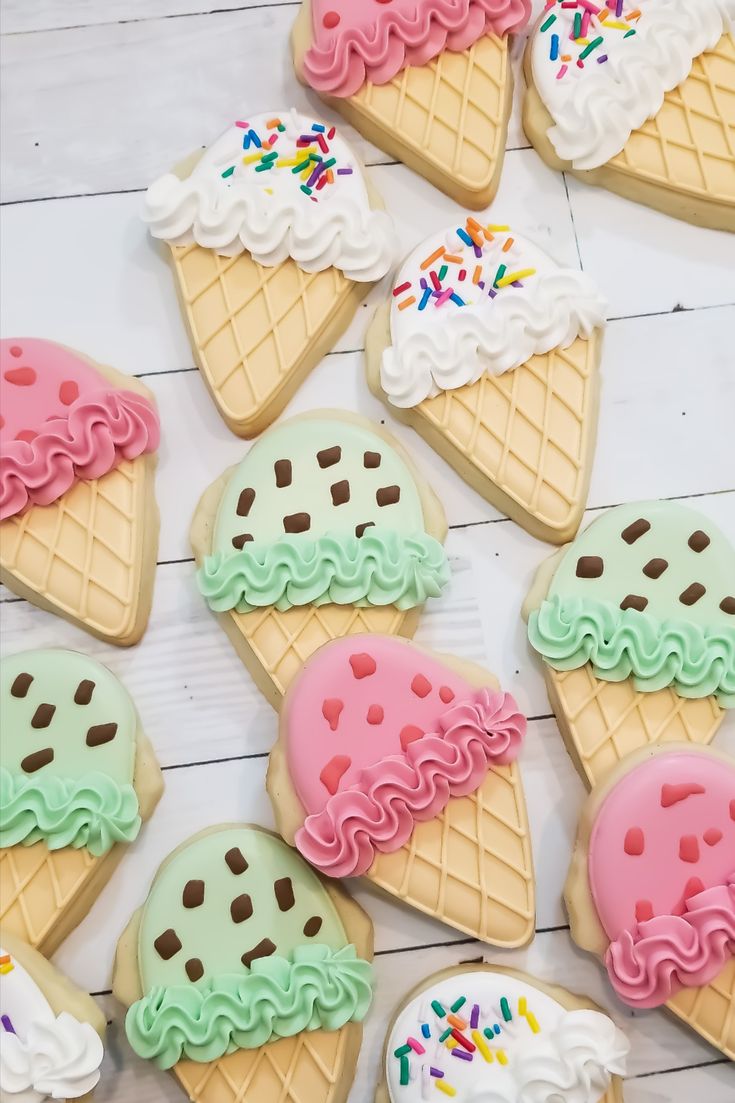 some ice cream and cookies are arranged on a white wooden table with sprinkles