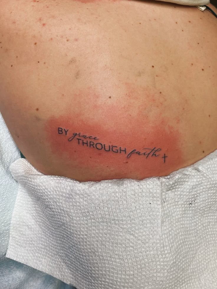 the back of a woman's shoulder with an inscription on it that says, by through faith