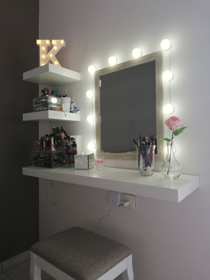 a vanity mirror with lights on it and a stool in front of the mirror that is lit up