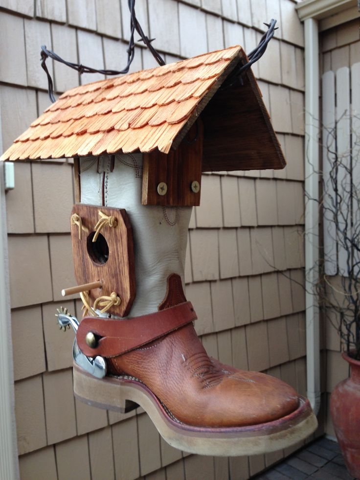 a birdhouse made out of boots hanging from the side of a house