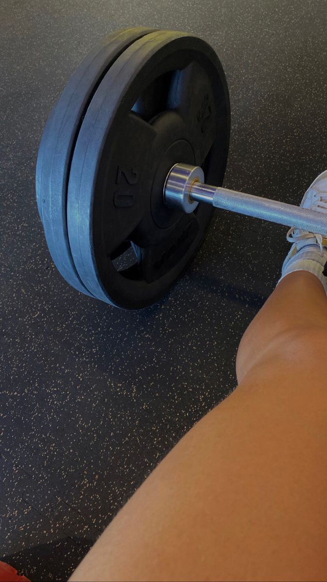 a person holding a barbell in their right hand and sitting on the ground next to them