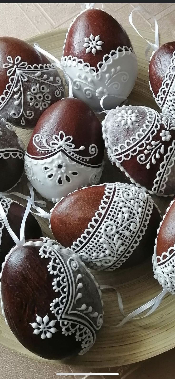 several decorated chocolate eggs on a plate with white lace around the edges and sides,