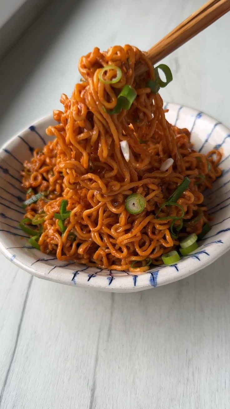 a white plate topped with noodles and chopsticks