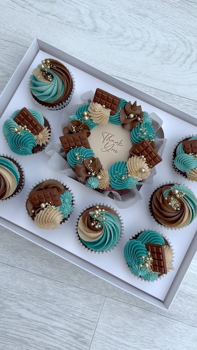 a box filled with cupcakes on top of a wooden floor next to a white table