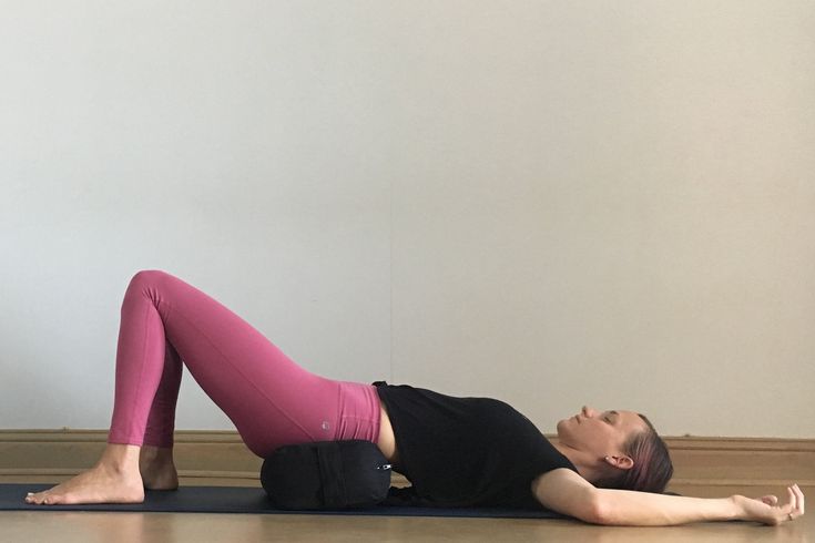 a woman in pink pants and black shirt doing a yoga pose