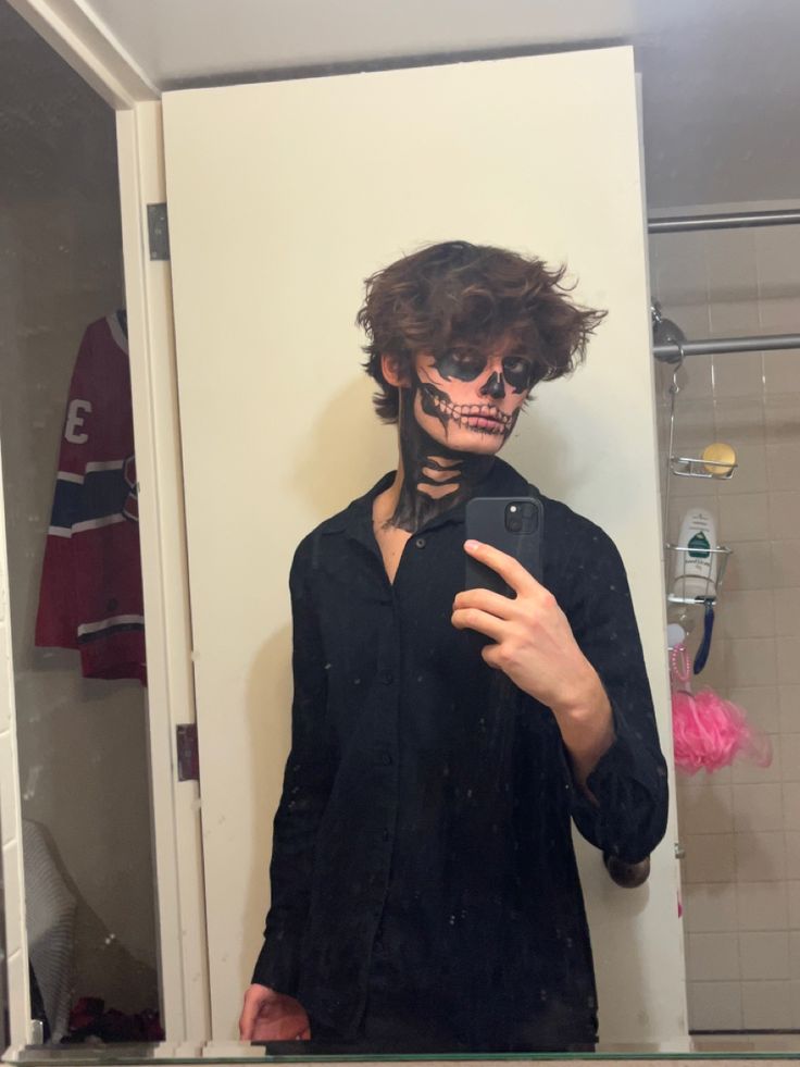 a man with his face painted like a skeleton taking a selfie in the mirror