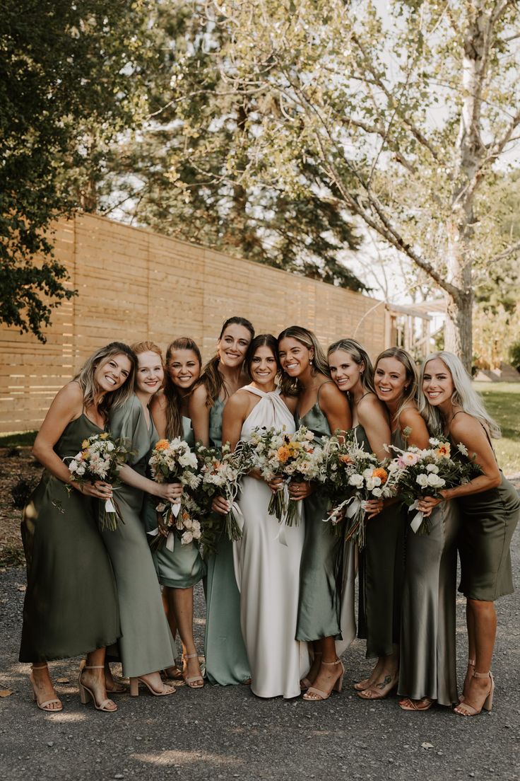 a group of women standing next to each other wearing dresses and holding bouquets in their hands