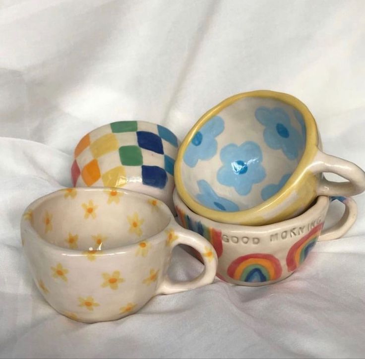 three cups and saucers sitting on top of a white sheet