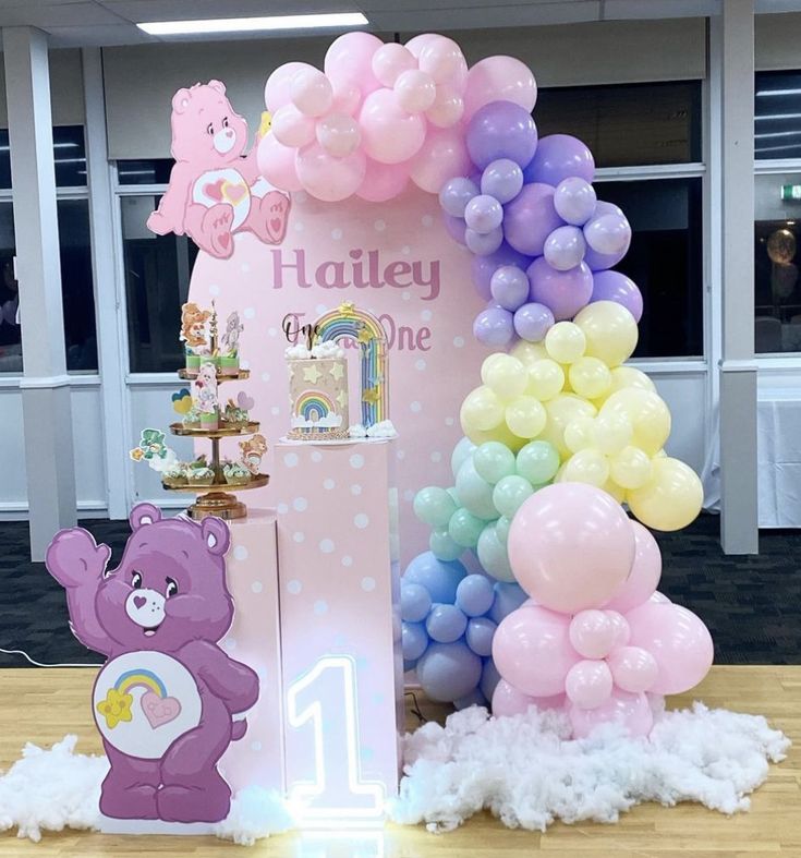 a table with balloons and decorations for a 1st birthday party at a children's playroom