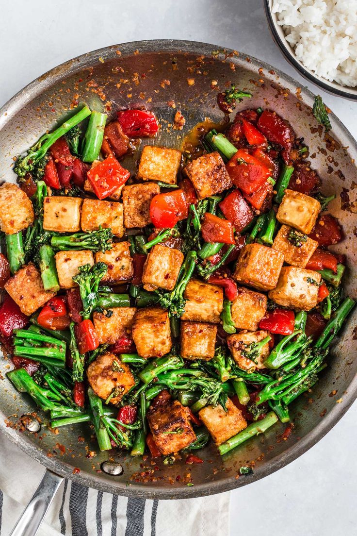 tofu and broccoli stir fry in a pan with rice on the side