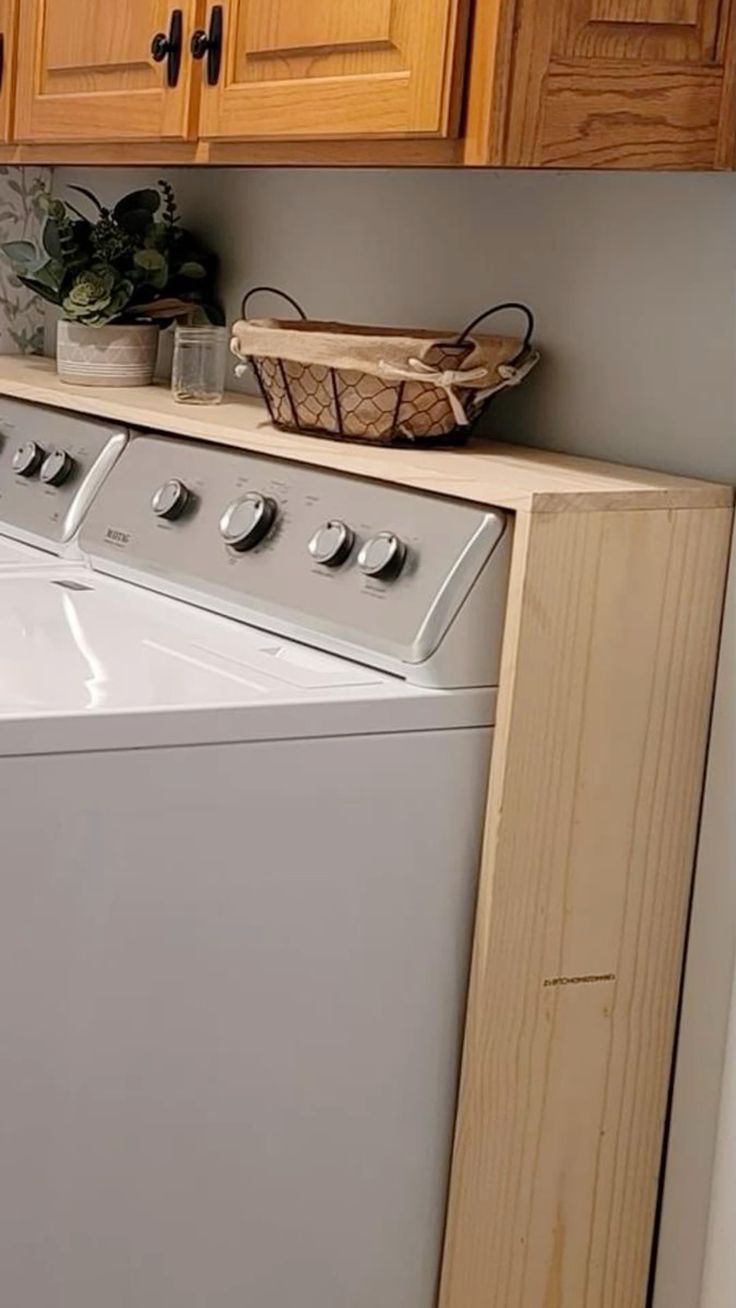 a washer and dryer sitting in a kitchen next to wooden cupboards on the wall