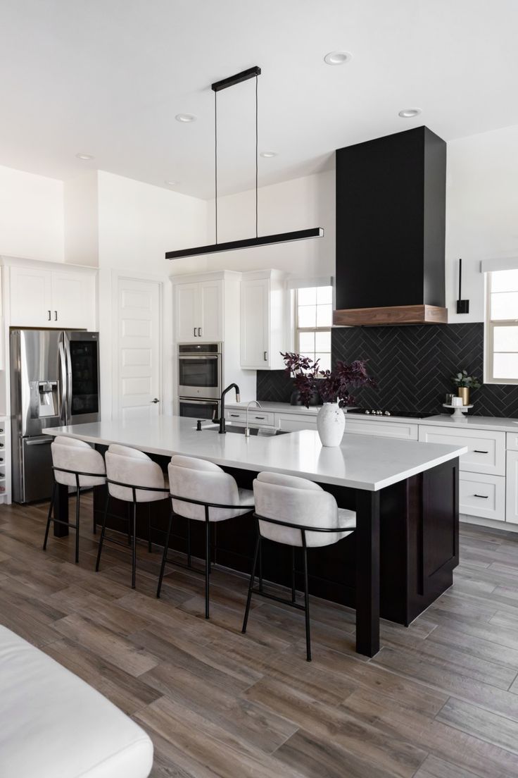 a kitchen with an island, stove and refrigerator in it's center area that has white chairs around the table