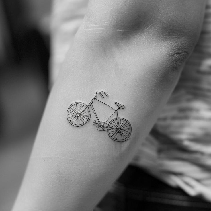 a black and white photo of a person with a bicycle tattoo on their arm,