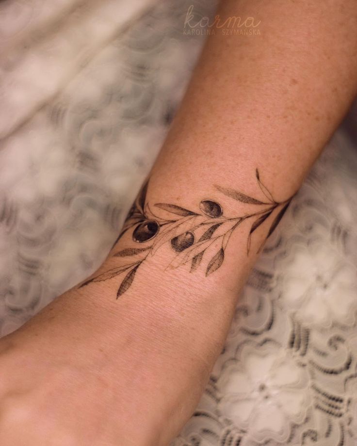 a woman's arm with an olive branch tattoo on it