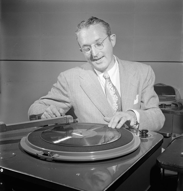 a man in a suit and tie sitting at a table with a record player on it