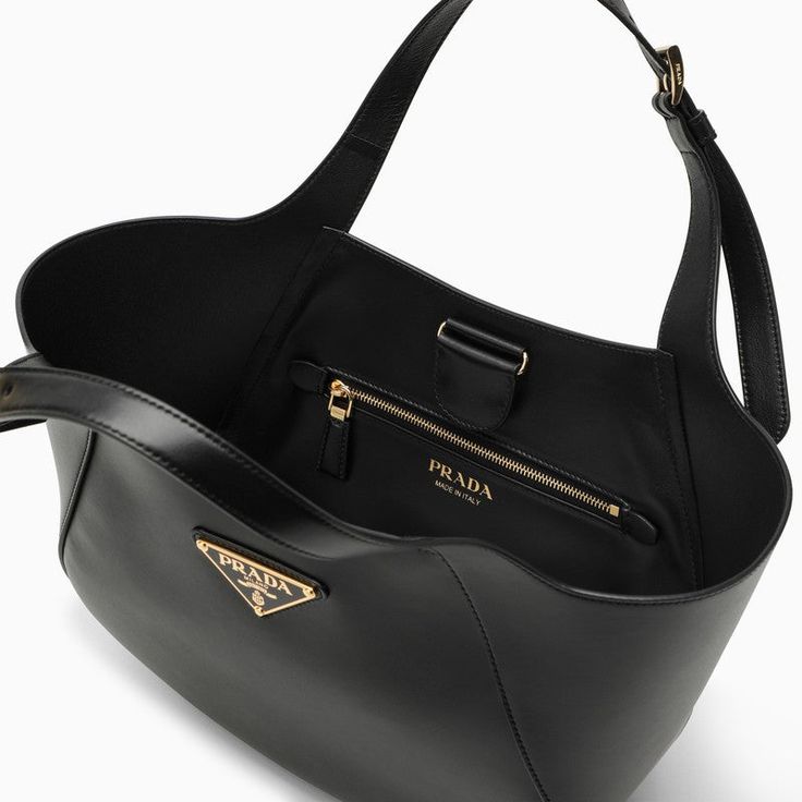 Black leather Prada tote bag featuring adjustable leather handles, enamelled metal logo triangle on the front, magnetic closure and nappa leather interior with zipped pocket. Width 25 cm x Height 19 cm x Depth 9 cm Handle drop 15 cm Size Type: INTMaterial: LeatherSKU: 1BG483OOO2AIX/O_PRADA-F0002_100 Our Products Are 100% Genuine. In All Cases We Stand By The Authenticity Of Every Product Sold On Our Site. Logo Triangle, Balenciaga Backpack, Prada Tote Bag, Medium Tote Bag, Bottega Veneta Shoulder Bag, Medium Tote, Metal Logo, Leather Handles, Metallic Logo