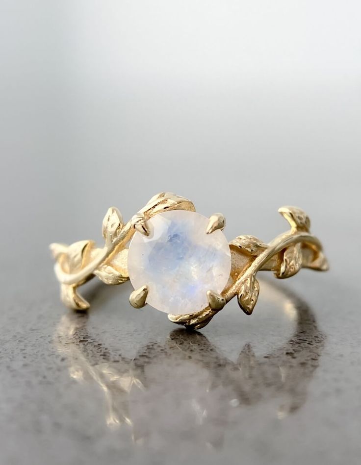 This leaf moonstone ring is intricately designed in 14k gold plating over sterling silver. It is a very unique piece just like the person wearing it! Moonstone is considered to be a stone of "New Beginnings". It can help you stabilize your emotions and enhance your intuition. Delicate Jewelry With Ring Detail As A Gift, Elegant Handmade 14k Gold Crystal Ring, Handmade Elegant Moonstone Stackable Rings, Elegant Handmade Moonstone Stackable Rings, Stackable Moonstone Promise Ring Jewelry, Elegant Handmade Stackable Moonstone Rings, Oval Stackable Jewelry For Promise, Adjustable Heirloom Jewelry With Ring Detail, Classic Moonstone Open Ring For Promise