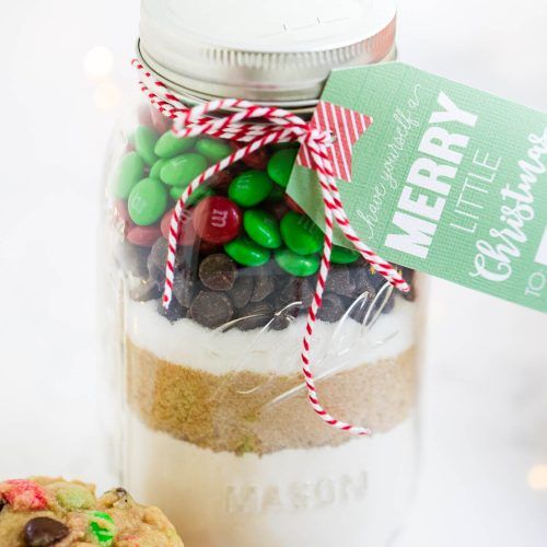 a jar filled with lots of candy sitting on top of a table next to a cookie