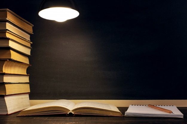 a stack of books sitting on top of a wooden table next to a light bulb