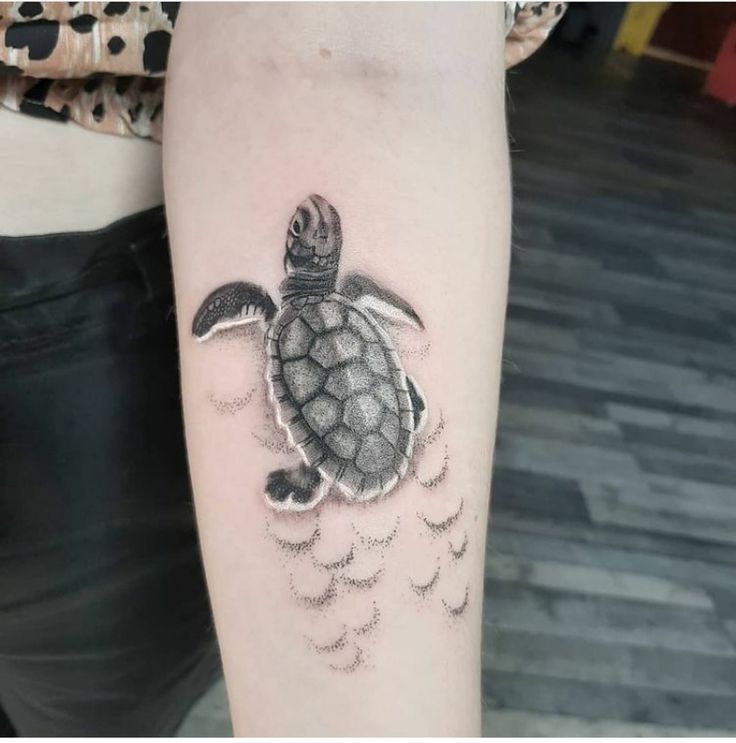 a small turtle tattoo on the arm