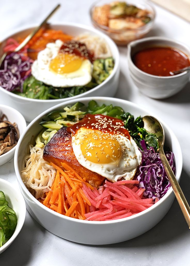 three white bowls filled with different types of food and sauces on top of a table