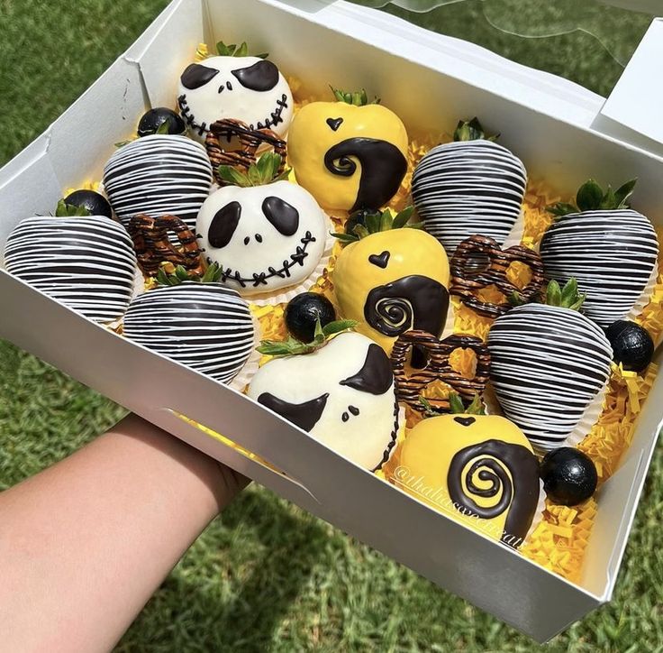 a box filled with lots of yellow and black decorated chocolate covered in white frosting