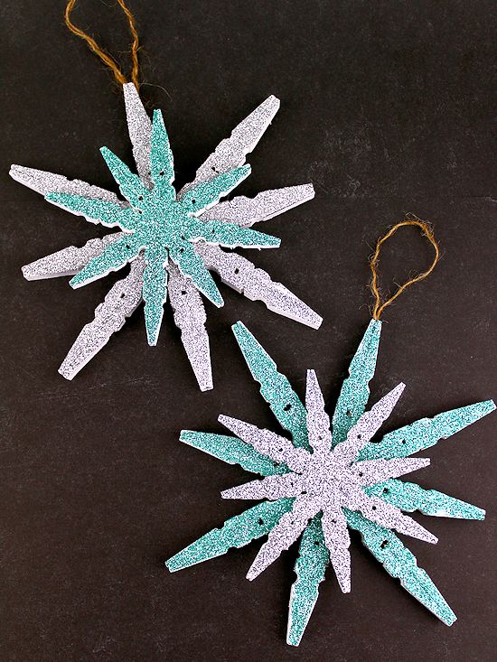 two paper snowflakes are sitting on a black surface, one is blue and the other is white