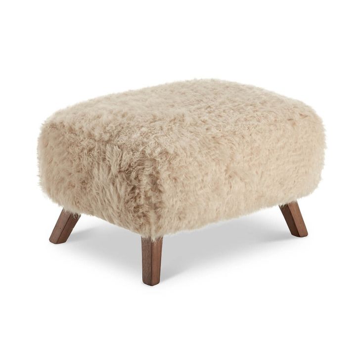 a sheepskin footstool with wooden legs on an isolated white background, side view