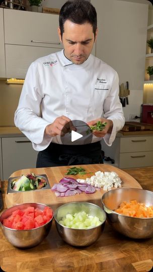 a man in a chef's uniform preparing food on top of a wooden table