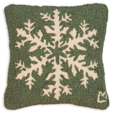 a green pillow with white snowflakes on it