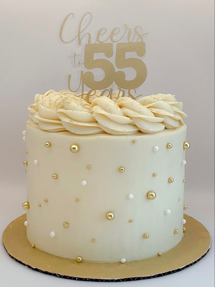 55th birthday cake with custom gold topper. Cream colored buttercream with piped ring on top with gold glitter and gold decorations 50th Birthday Cake White And Gold, White Golden Cake Design, Women’s Cake Ideas, 60th Buttercream Birthday Cake, White And Gold Cake Graduation, Simple White Birthday Cake Design, Small 60th Birthday Cake, Birthday Cake 2 Tier Simple, White And Gold Buttercream Cake