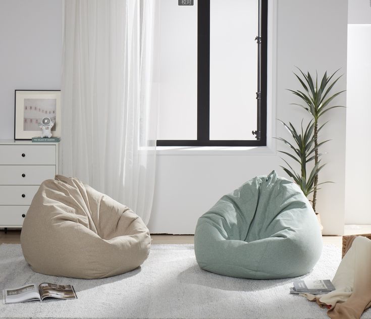 two bean bag chairs sitting on top of a white rug in front of a window