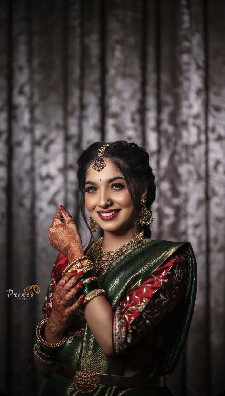 a woman in a green and red sari holding her hands up to her chest