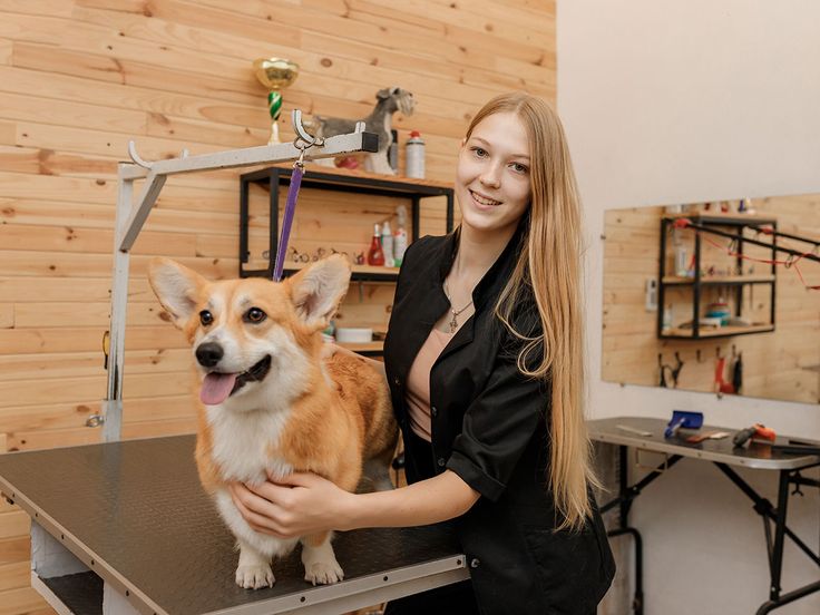 a woman standing next to a small dog on top of a table in a room