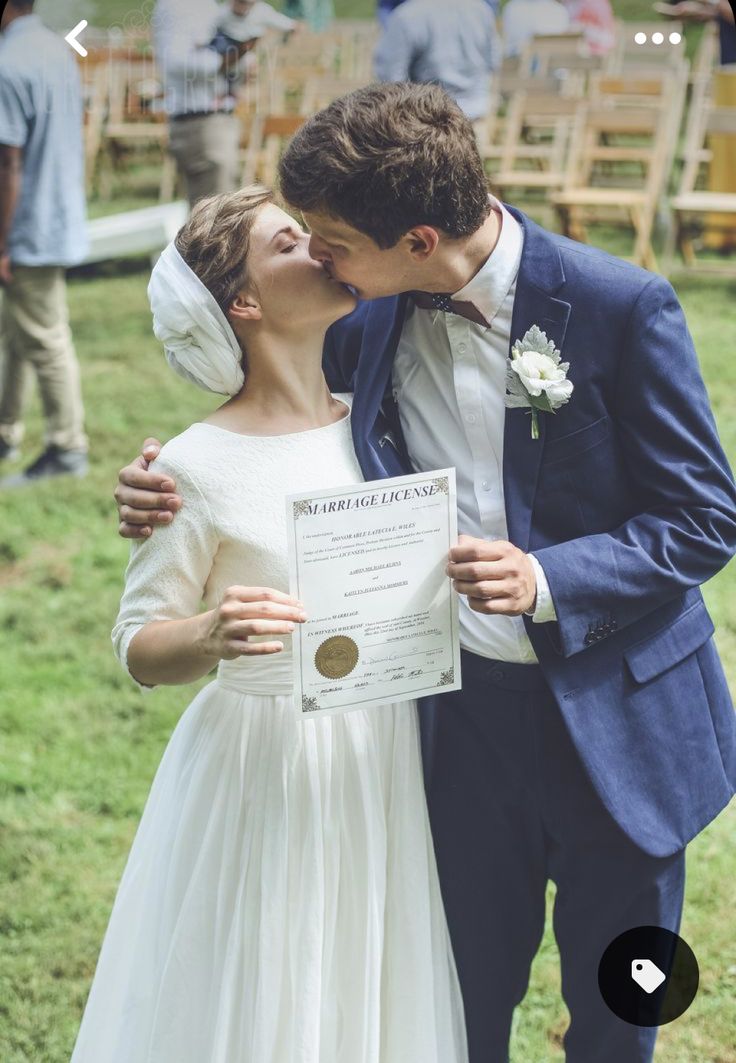 a man and woman kissing each other while holding a certificate