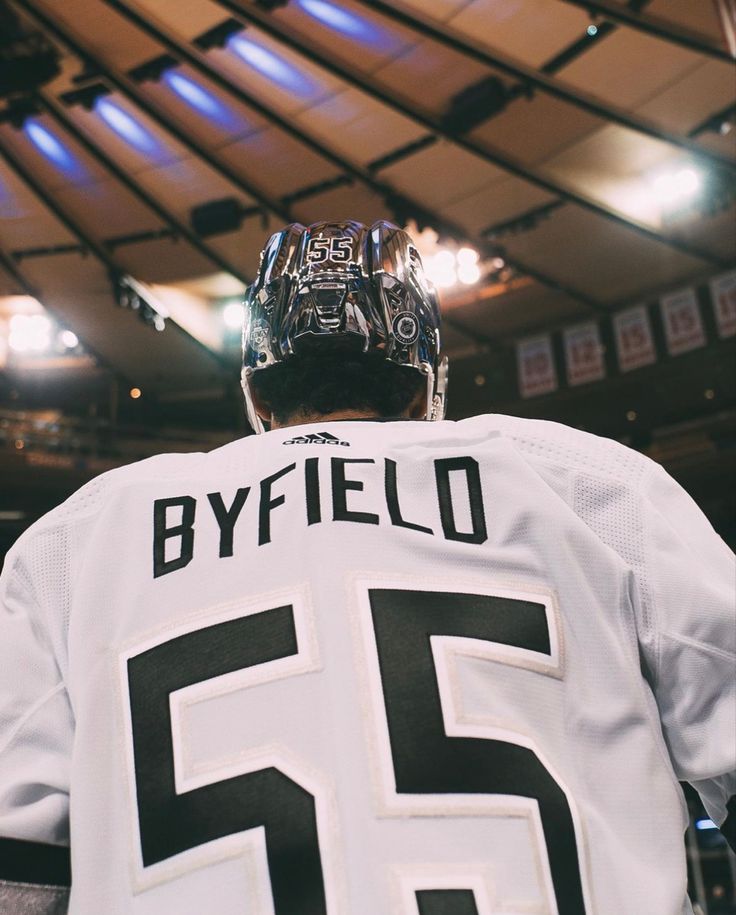 the back of a hockey player's white jersey with black numbers on it and lights in the background