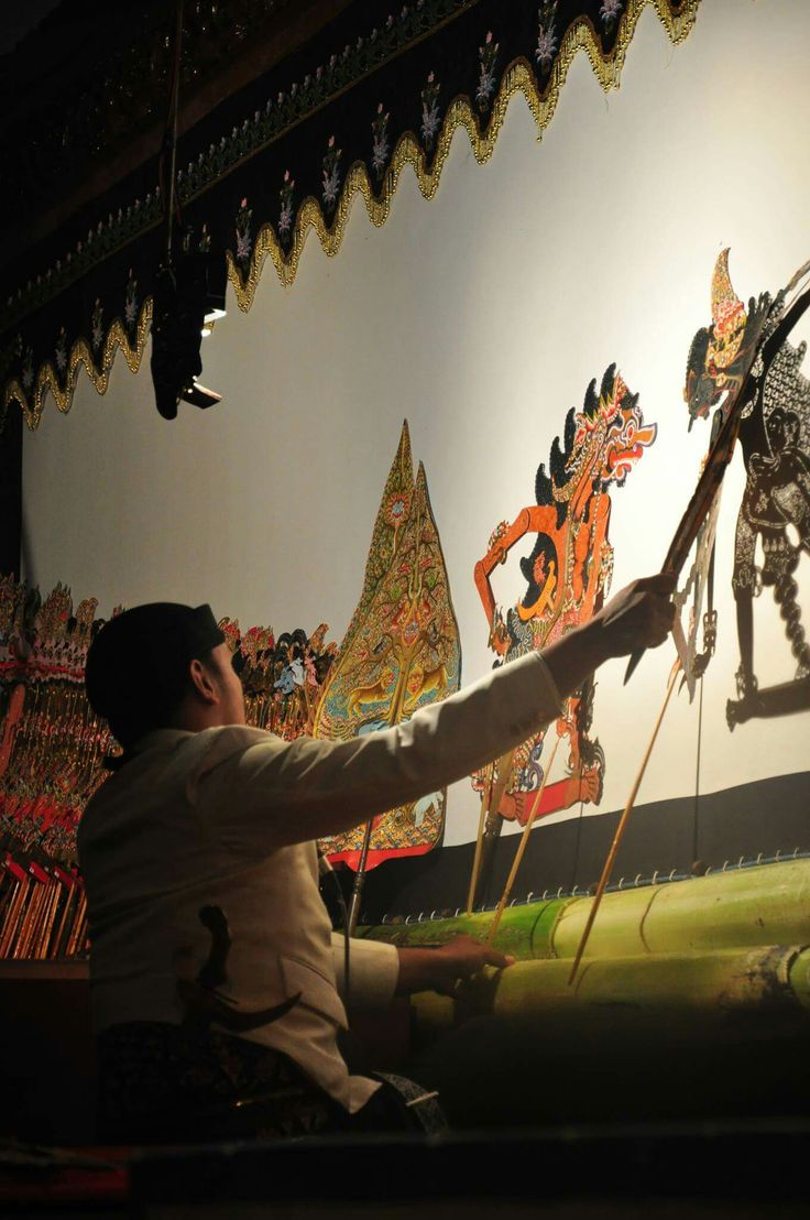 a man sitting on top of a bench next to a wall covered in pictures and paintings