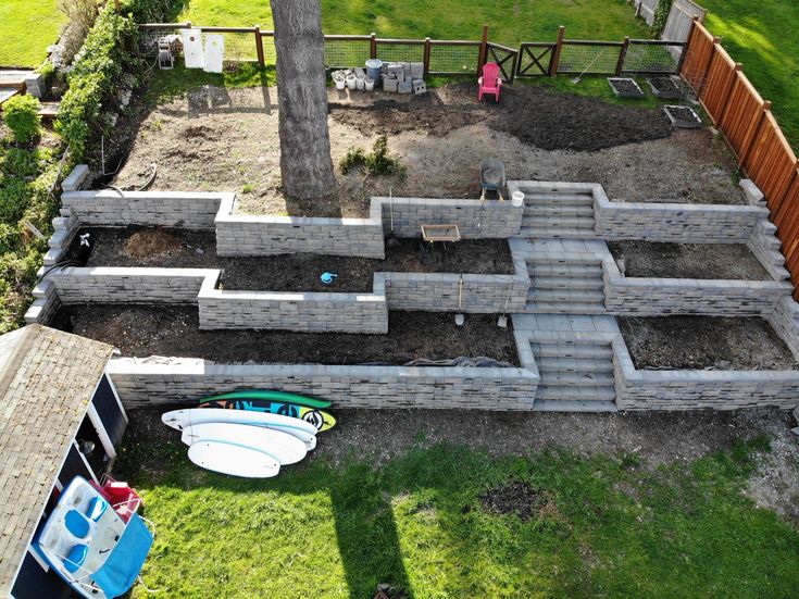 an aerial view of a backyard with concrete blocks and surfboards