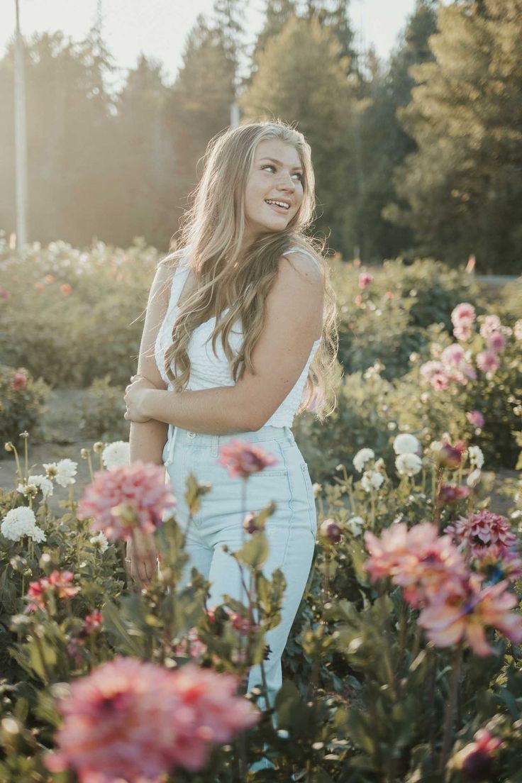 a beautiful young woman standing in a field of flowers