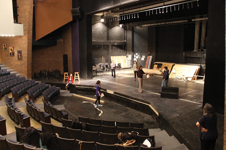 people are standing on the stage in an empty auditorium with chairs and other things around them