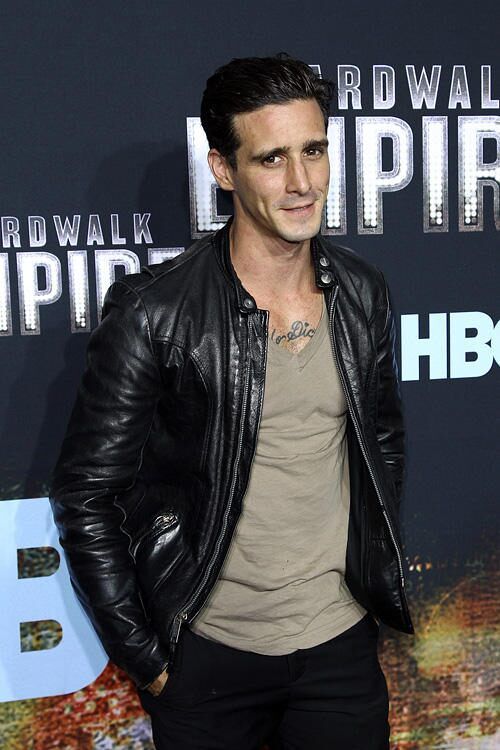 a man in black leather jacket standing on red carpet