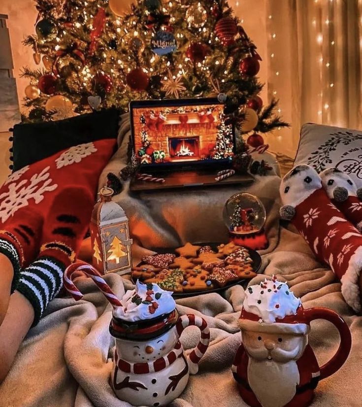 two teapots are sitting on a blanket in front of a decorated christmas tree