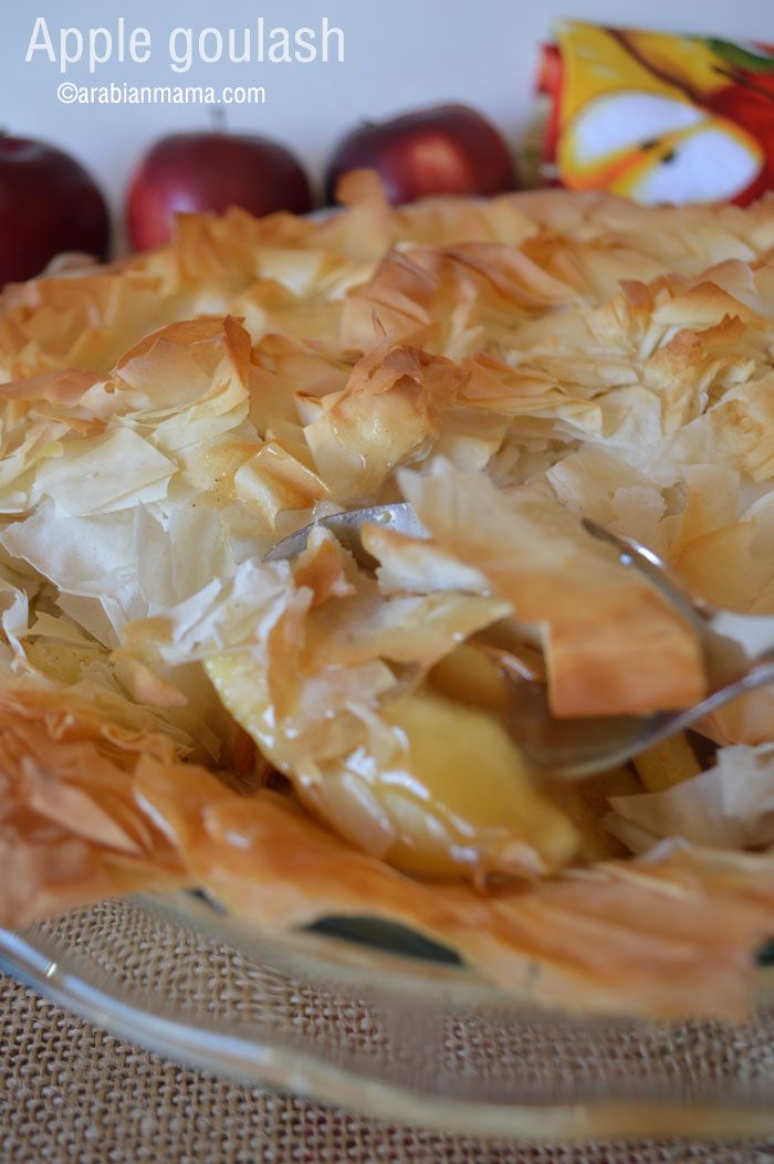 an apple goulash pie on a glass plate with apples in the back ground