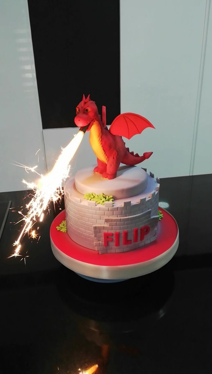 a birthday cake with a red dragon on top and sparklers in the air above it