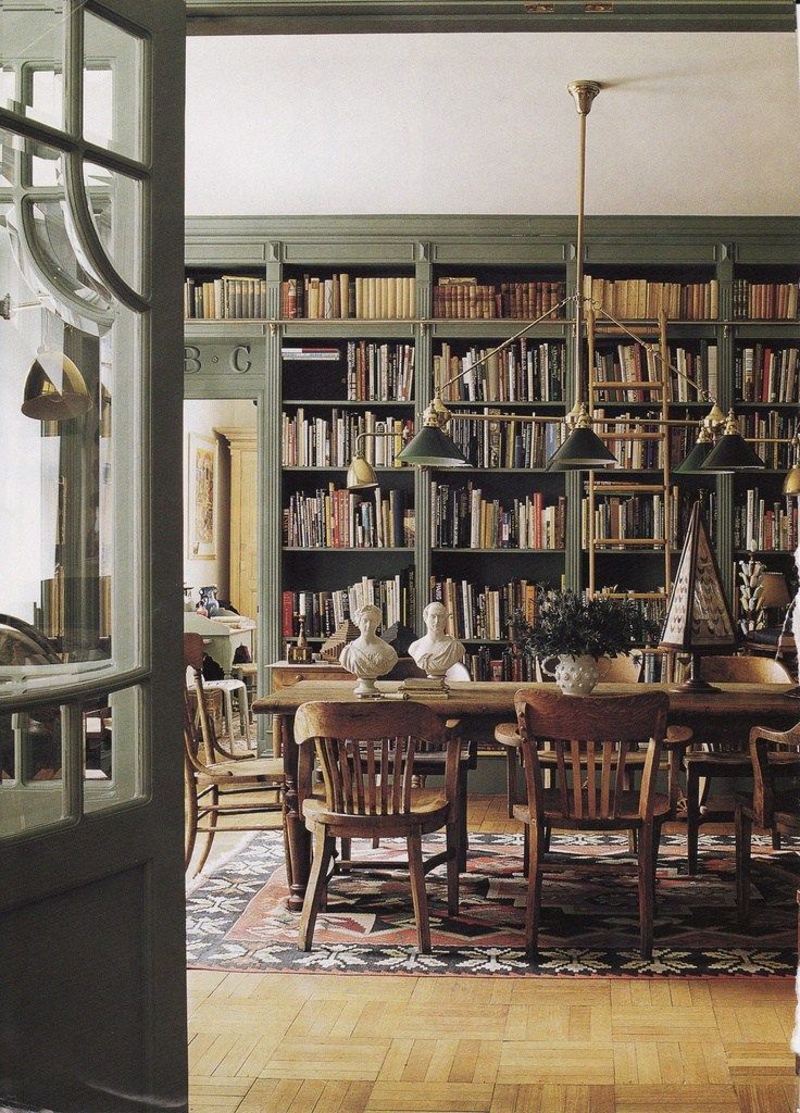 a dining room table and chairs in front of a bookshelf filled with books