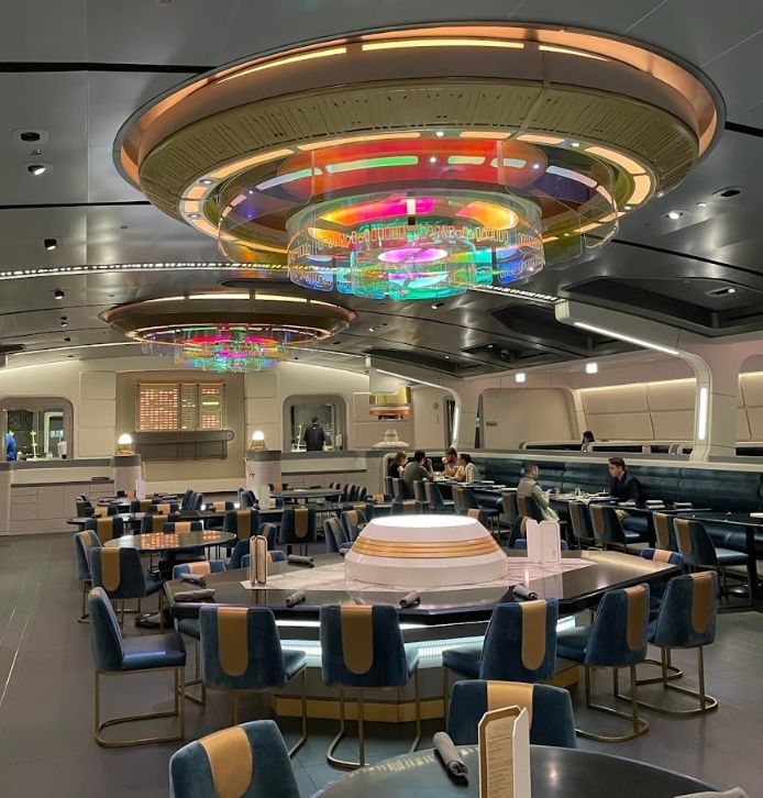 a large dining room filled with lots of blue chairs and round tables covered in colorful lights