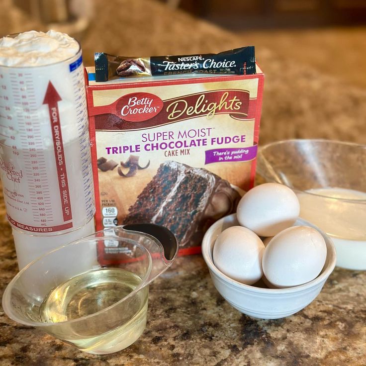 ingredients to make chocolate cake sitting on a counter top next to an egg carton