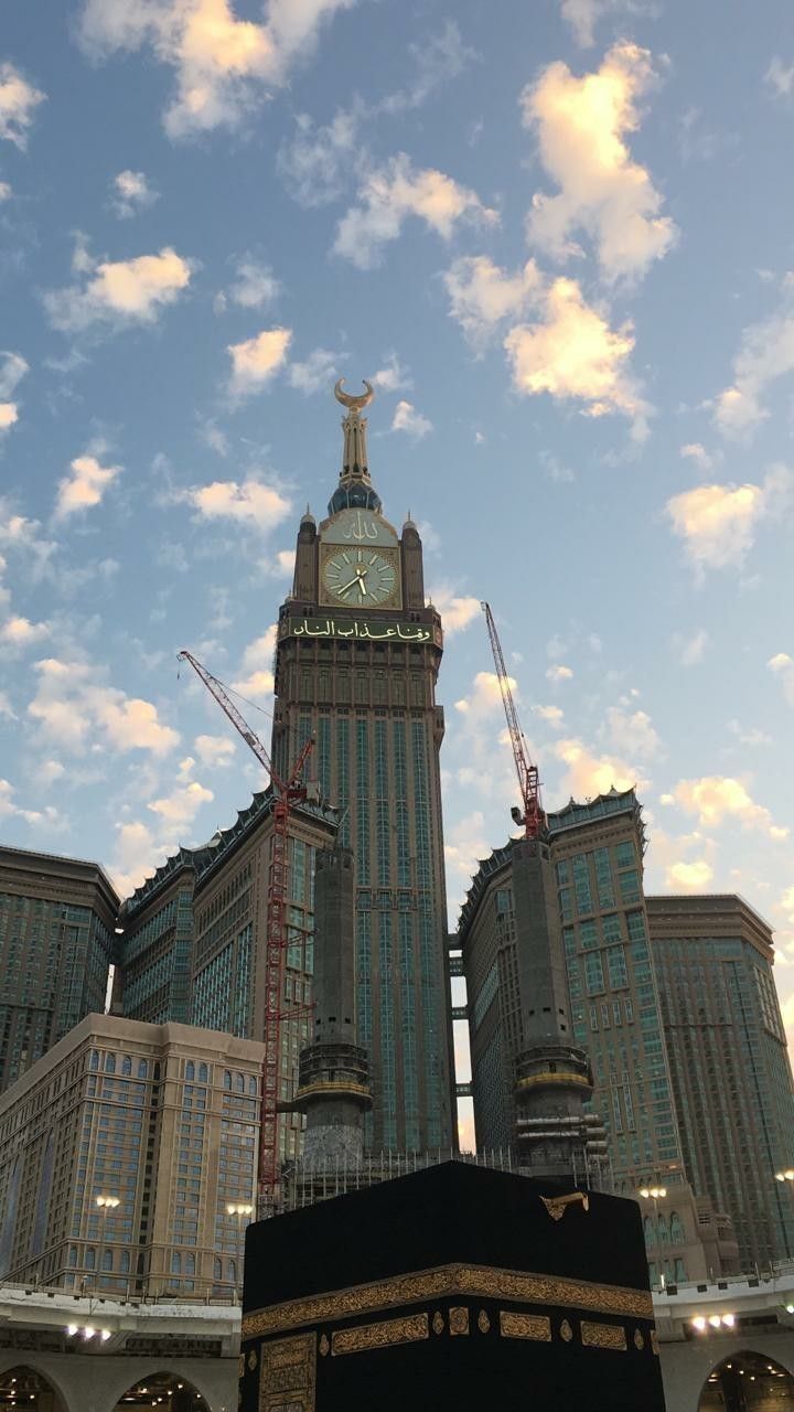 a large clock tower towering over a city under a cloudy blue sky with white clouds