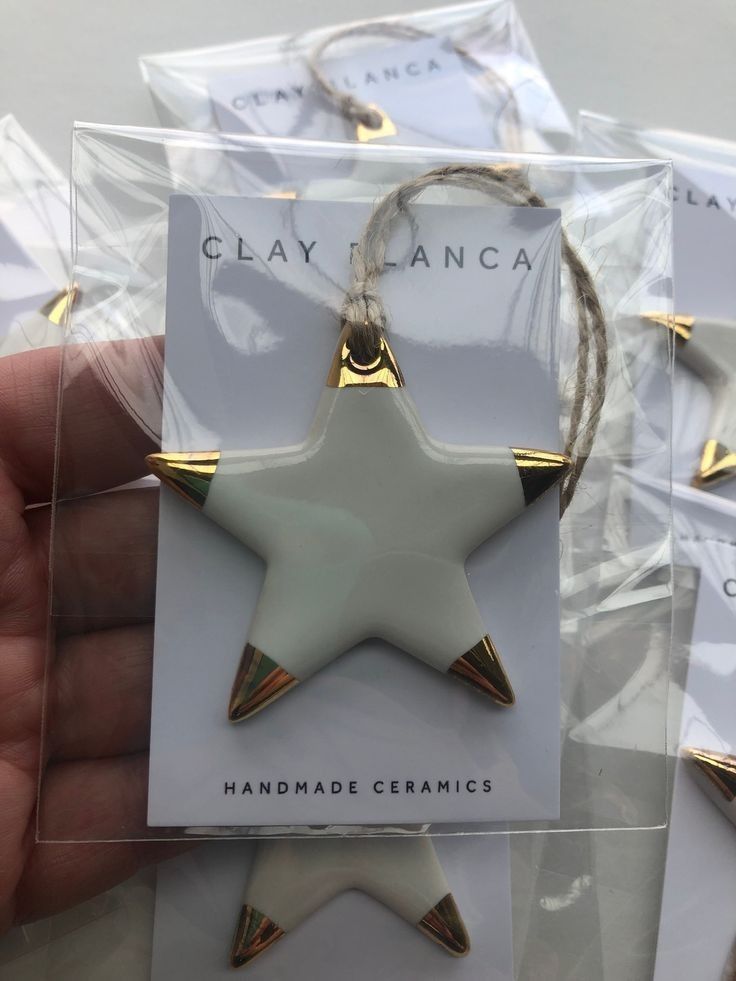 a hand holding a white and gold star ornament in front of packaged packages