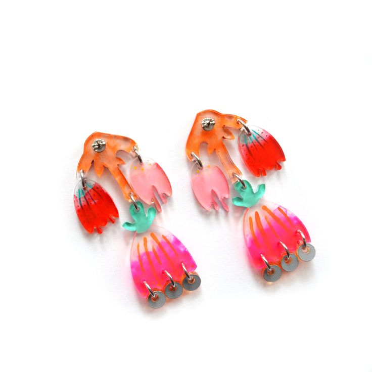 two pairs of colorful earrings on a white surface